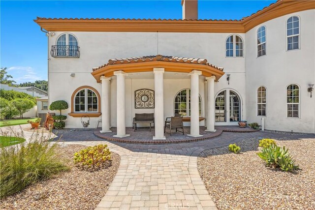 view of exterior entry with a patio area and central AC unit