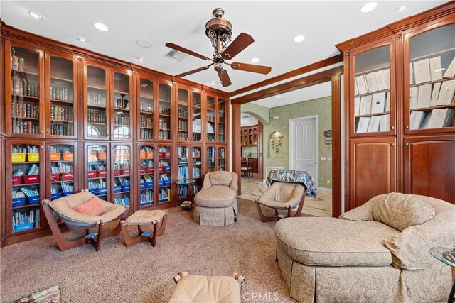 living area featuring carpet, crown molding, and ceiling fan