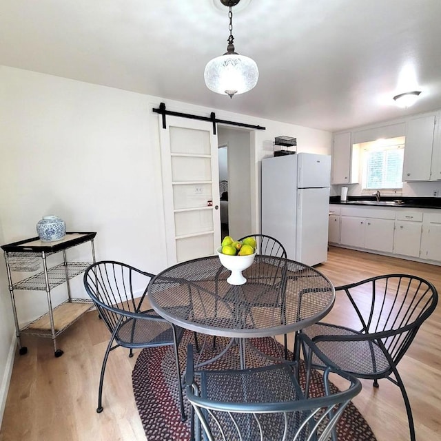 dining room with a barn door, light hardwood / wood-style floors, and sink