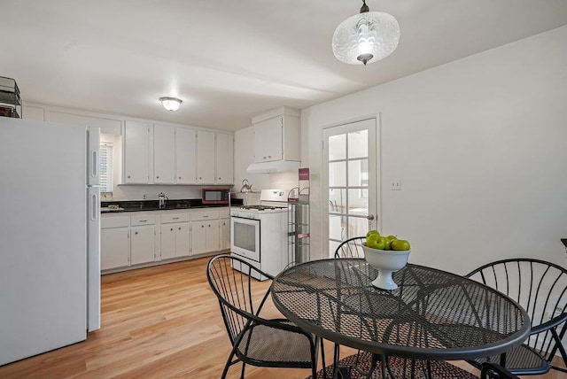 kitchen featuring white cabinets, decorative light fixtures, light wood-type flooring, and white appliances