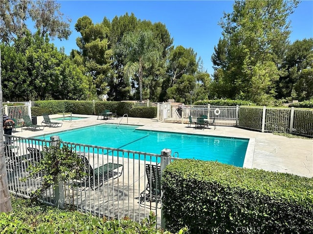 pool with a patio area and fence