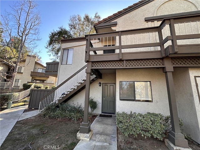 property entrance featuring a tile roof and stucco siding