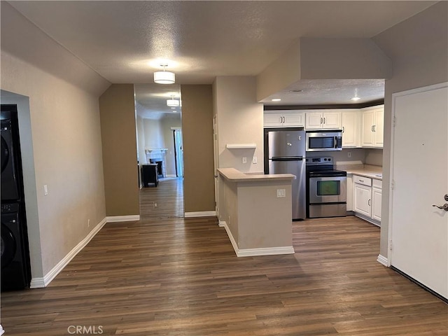 kitchen with white cabinets, a textured ceiling, appliances with stainless steel finishes, dark hardwood / wood-style flooring, and stacked washer / dryer