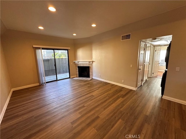 unfurnished living room featuring a fireplace, dark wood finished floors, visible vents, and baseboards