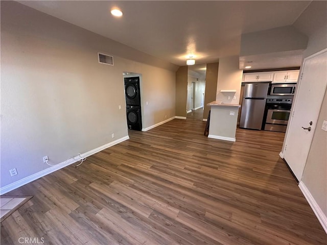 kitchen featuring stacked washer / drying machine, visible vents, appliances with stainless steel finishes, open floor plan, and white cabinets