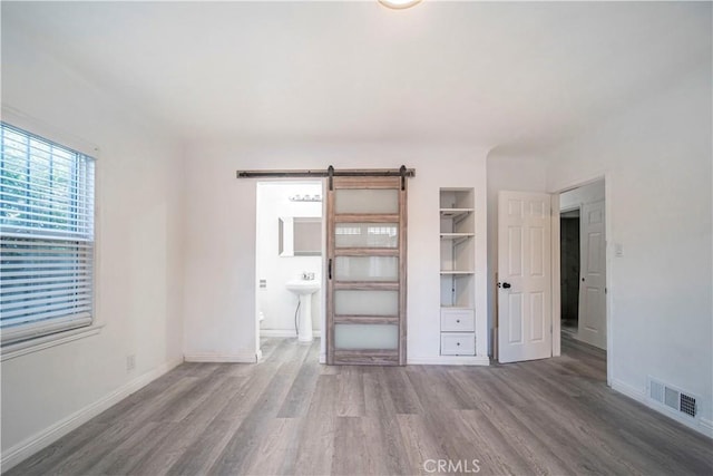 interior space with a barn door, connected bathroom, and hardwood / wood-style floors