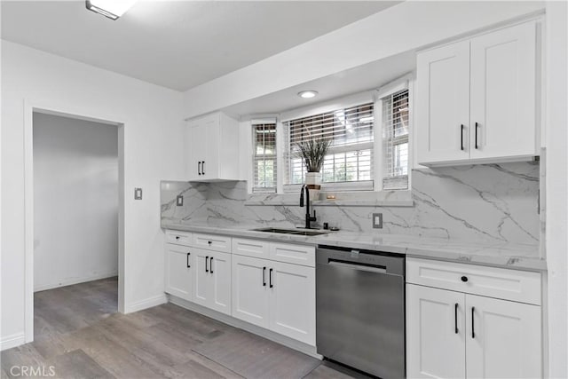 kitchen with white cabinetry, tasteful backsplash, stainless steel dishwasher, light stone counters, and sink