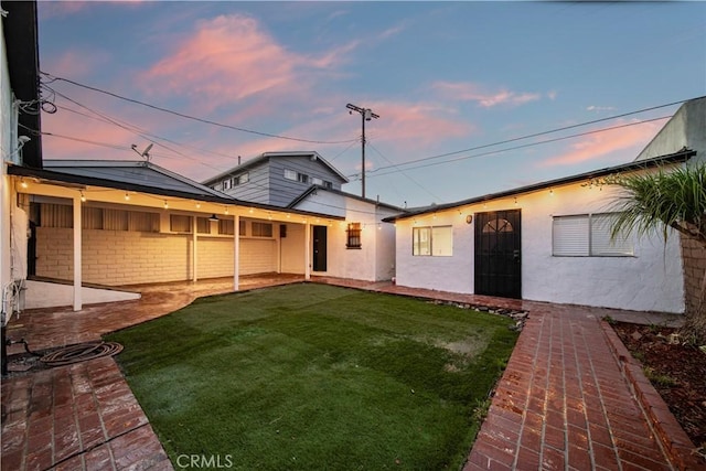 back house at dusk with a lawn