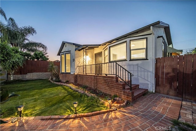 property exterior at dusk featuring a yard