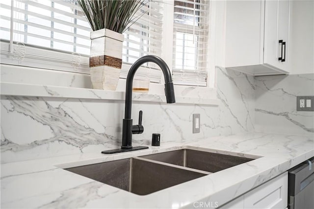 details with light stone counters, sink, white cabinetry, and tasteful backsplash