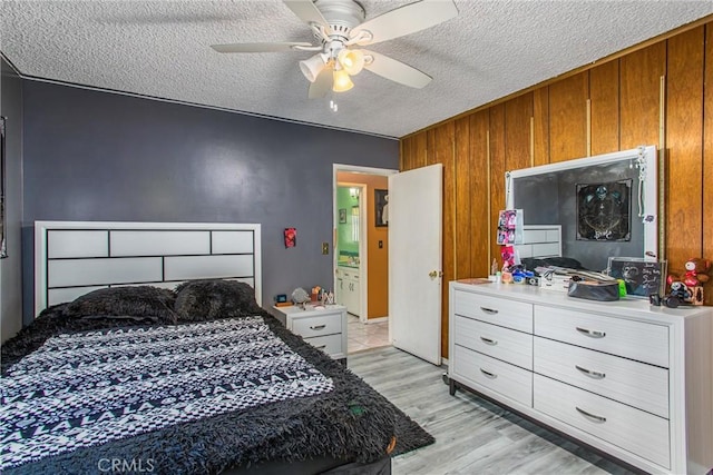 15937 Manzanita Dr, Fontana, CA 92335 - bedroom featuring a textured ceiling, wooden walls, a ceiling fan, and light wood-style flooring