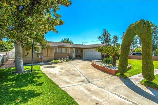 ranch-style home featuring a garage, fence, driveway, stucco siding, and a front yard