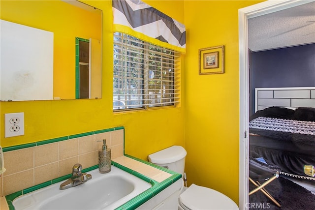 bathroom with a textured ceiling, vanity, and toilet