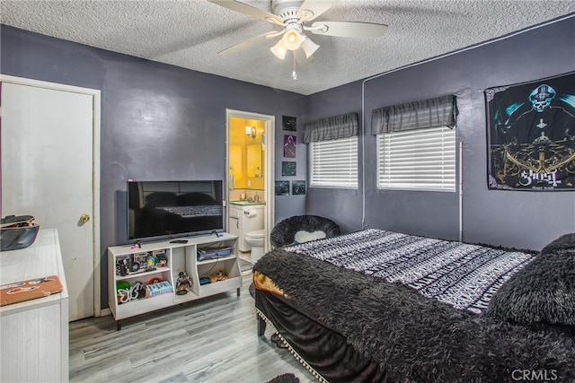 bedroom with ceiling fan, a textured ceiling, connected bathroom, and hardwood / wood-style floors