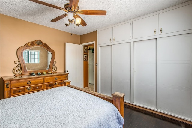 bedroom featuring ceiling fan, a textured ceiling, and dark wood-type flooring