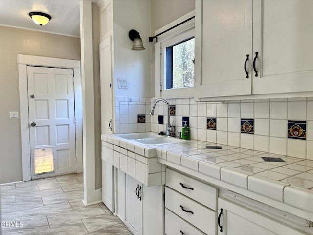 kitchen with tile countertops, decorative backsplash, sink, and white cabinets