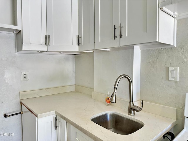 kitchen with white cabinets, light stone countertops, and sink