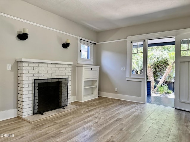 unfurnished living room with a fireplace, light wood-type flooring, and plenty of natural light