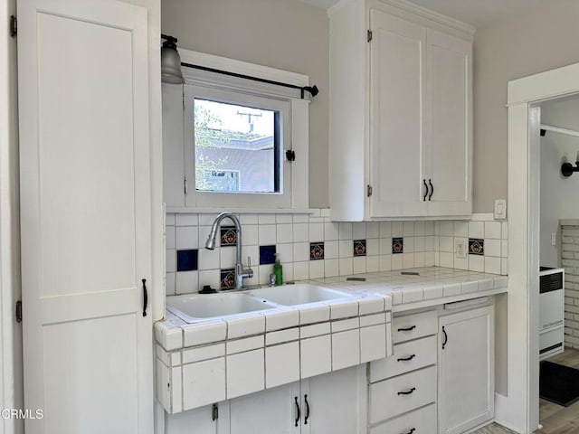 kitchen featuring white cabinetry, tile counters, light hardwood / wood-style flooring, and sink