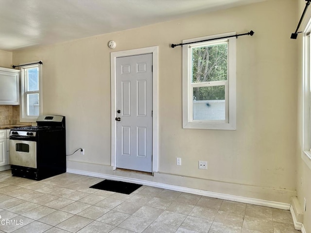 kitchen with gas stove, white cabinets, light tile patterned floors, and a baseboard heating unit