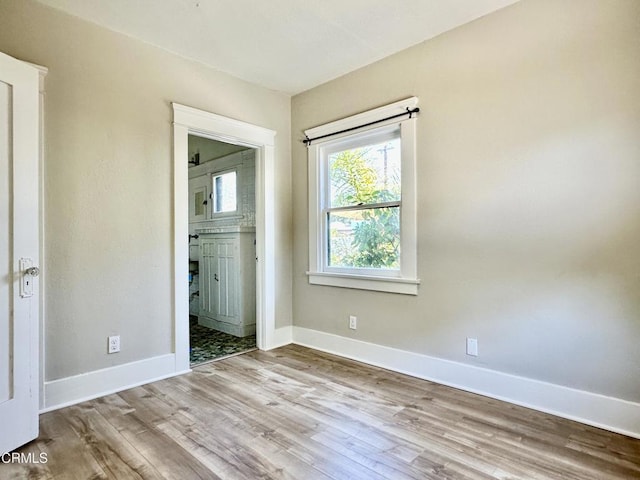 unfurnished bedroom featuring ensuite bathroom and light wood-type flooring