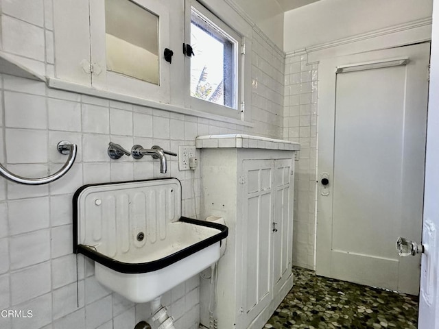 bathroom with sink and tile walls