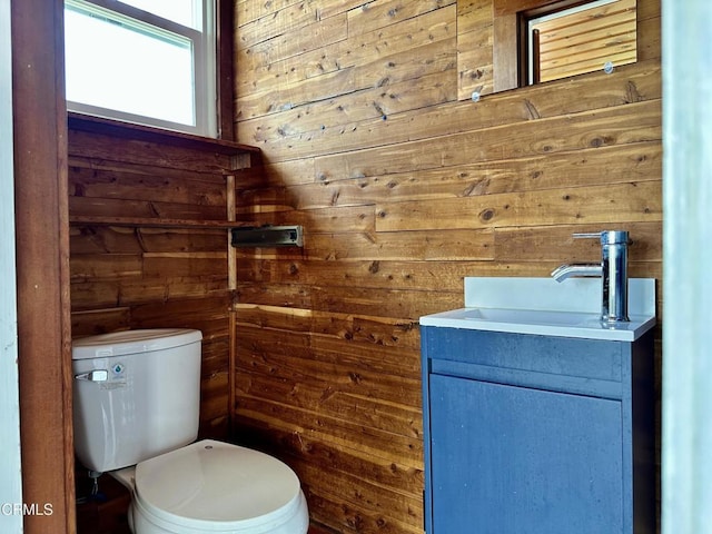 bathroom featuring vanity, toilet, and wooden walls