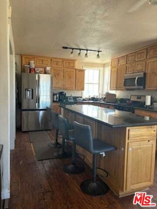 kitchen with stainless steel appliances, dark hardwood / wood-style floors, and a breakfast bar