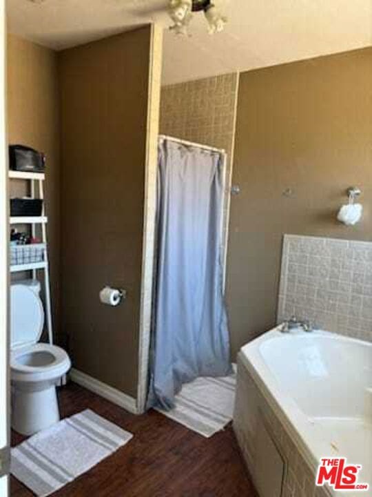 bathroom with independent shower and bath, toilet, and hardwood / wood-style flooring