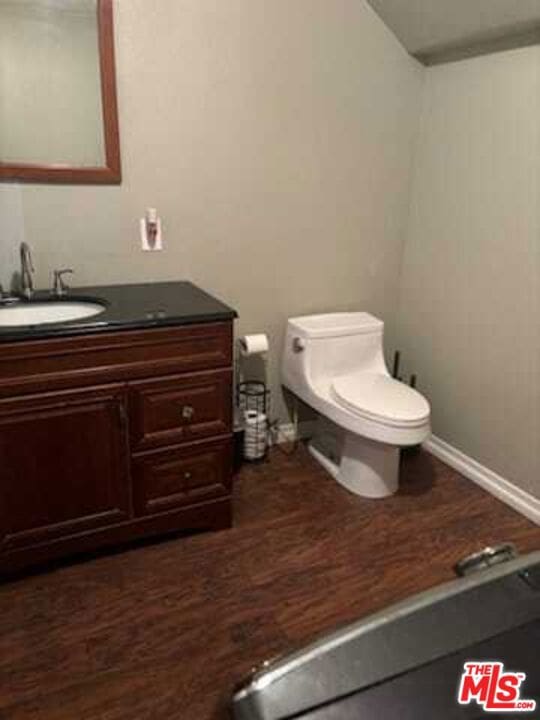 bathroom with wood-type flooring, vanity, and toilet