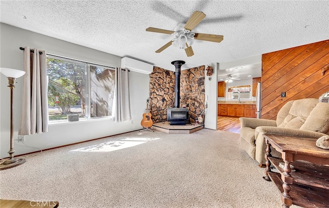 carpeted living room featuring a wood stove, a textured ceiling, ceiling fan, and a wall mounted air conditioner