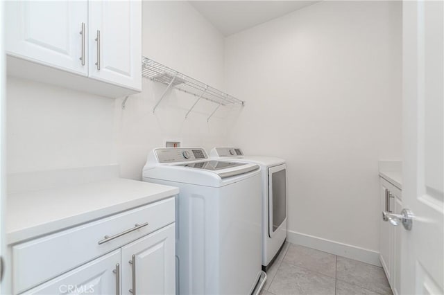 laundry room with separate washer and dryer, light tile patterned floors, and cabinets