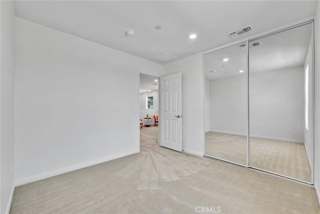 unfurnished bedroom featuring light carpet and a closet