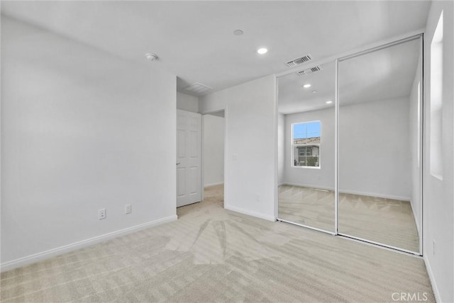 unfurnished bedroom with light carpet and a closet