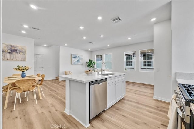 kitchen featuring a kitchen island with sink, white cabinets, sink, light wood-type flooring, and appliances with stainless steel finishes