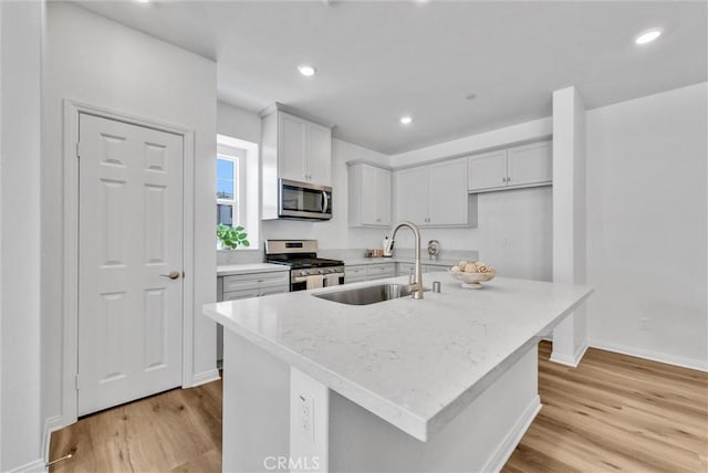 kitchen with appliances with stainless steel finishes, a center island with sink, light hardwood / wood-style flooring, and sink