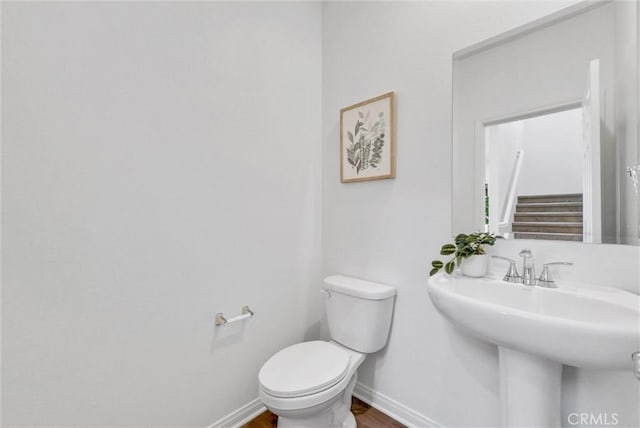 bathroom with hardwood / wood-style flooring, toilet, and sink