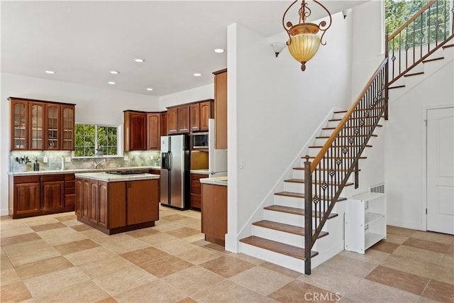 kitchen featuring pendant lighting, sink, a kitchen island, appliances with stainless steel finishes, and decorative backsplash