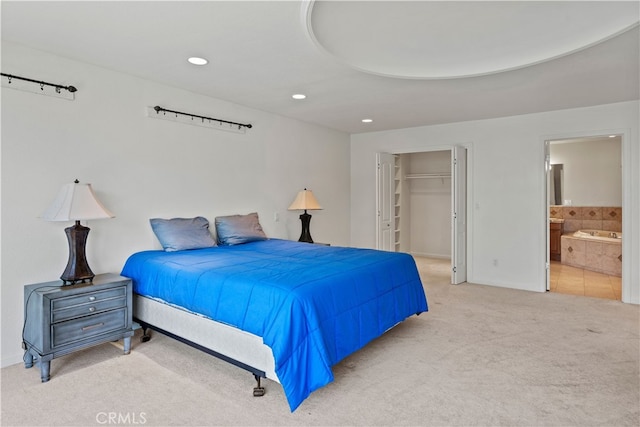 bedroom featuring light carpet, a closet, ensuite bath, and a walk in closet