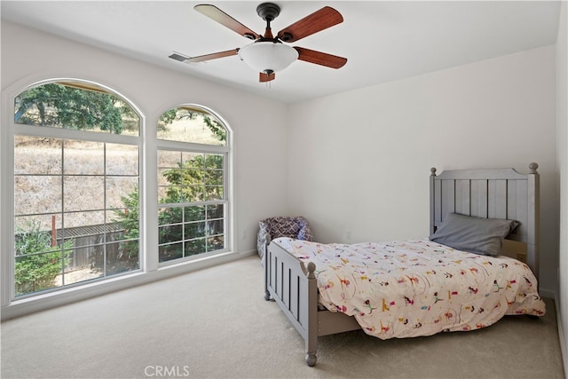 bedroom featuring multiple windows, ceiling fan, and light colored carpet