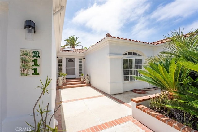 property entrance featuring stucco siding and a tiled roof