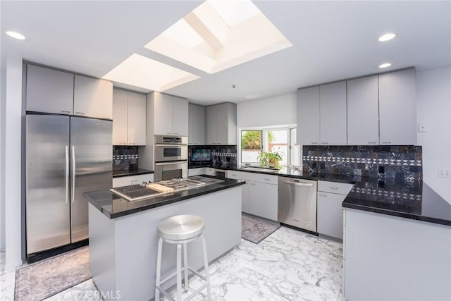 kitchen featuring stainless steel appliances, dark countertops, recessed lighting, and marble finish floor
