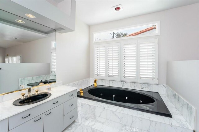 bathroom featuring a jetted tub, marble finish floor, and vanity