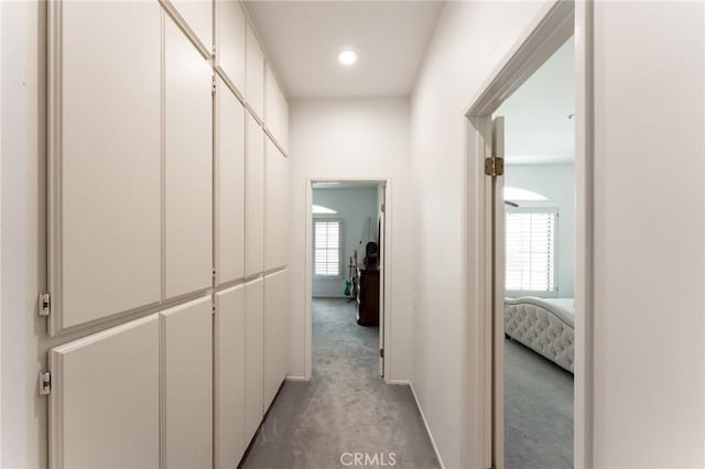 hall featuring recessed lighting, baseboards, light colored carpet, and a wealth of natural light