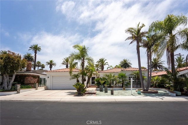 view of front facade with concrete driveway, an attached garage, a tile roof, and stucco siding