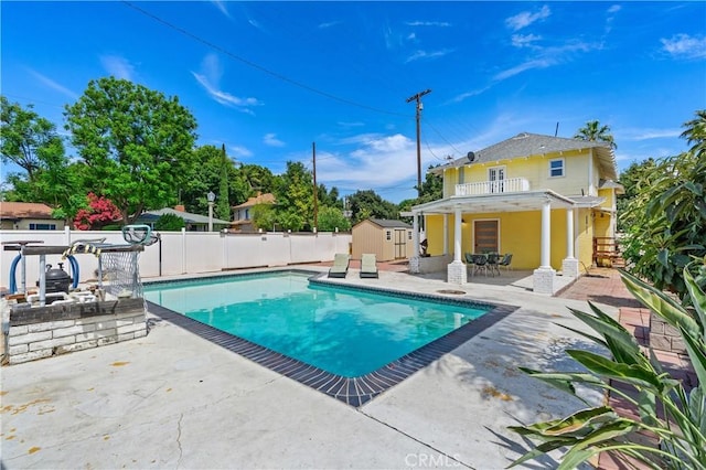 view of swimming pool with a patio and a storage shed