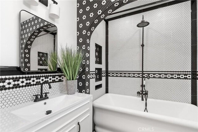 bathroom featuring backsplash, sink, a bath, and tile walls