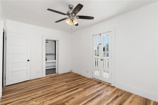 unfurnished bedroom featuring french doors, ensuite bath, access to outside, ceiling fan, and wood-type flooring