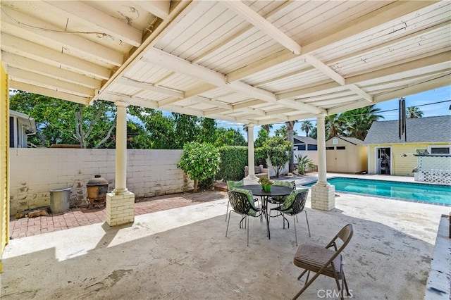 view of patio / terrace featuring a fenced in pool and a shed