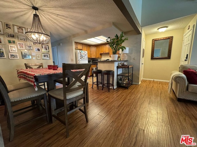 dining space featuring a textured ceiling, dark wood-type flooring, and a chandelier